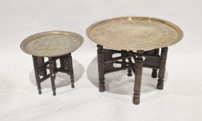 Indian circular brass tray-top table on carved folding stand and another smaller (2)