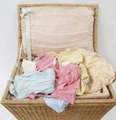 A vintage wicker nursery basket containing assorted mid and earlier 19th century baby clothes, to