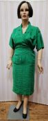 A vintage female mannequin, full figure, painted face and short wig, wearing a green linen wrap