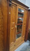 Edwardian pine wardrobe with mirrored front, flanked by carved foliate roundels above a drawer, on