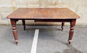Victorian mahogany extending dining table on four turned legs, raised on metal castors, with one