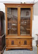 Stained oak carved bookcase, circa 1900, the double glazed doors above panelled twin cupboard