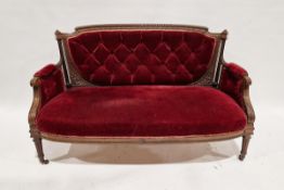 Late Victorian carved walnut two-seater salon sofa, upholstered in buttonback red velvet, with