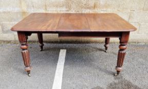 Victorian mahogany extending dining table on four turned legs, raised on metal castors, with one
