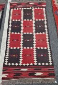 Two vintage Afghan rugs, each with chequerboard design in red and dark brown within cream lozenge-