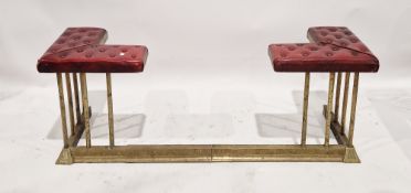 An early 20th century brass extending club fender upholstered in a burgundy leather fabric with