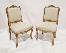 A pair of Louis XV style carved giltwood chairs, each with  cream damask upholstered seat and back