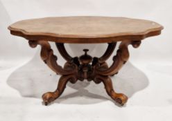 A Victorian figured walnut dining table, raised on four ornate scrolling legs with metal castors,