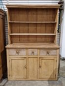 An antique pine kitchen dresser, the top section comprising two plate racks with attached hooks
