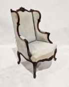An antique mahogany wing backed armchair, having ornate carved scrolling decoration to the finial