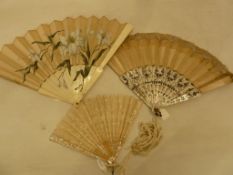 A painted satin fan with the decoration of lilies going onto the guards, a lace fan some stains