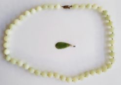 Green jade-coloured pendant, flowerhead carved, and a Chinese jade necklace with silver clasp (2)