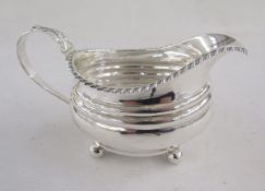 George IV silver milk-jug, of oval form with gadrooned rim and leaf terminal, raised on ball feet,