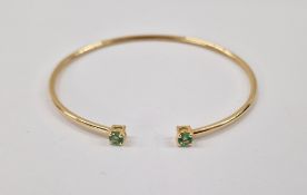 Gold-coloured metal and green stone bangle set two pale green stones, possibly emeralds