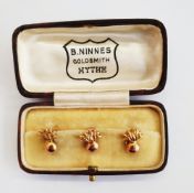Set of three gold-coloured studs of flaming ball pattern, makers mark 'BN', in case