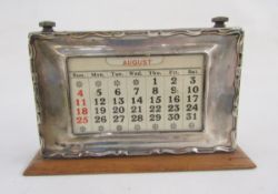 Silver mounted stained wood perpetual desk calendar, having raised scroll border, silver front