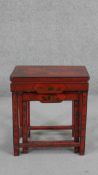 An early 20th century Chinese red lacquered nest of tables, rectangular with traditional designs