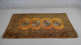 An Afghan gold wash rug with repeating gul motifs within stylised borders. L.183 W.105cm.