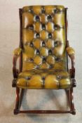 A mahogany slipper rocking chair, upholstered in green buttoned leather with studded edges, the legs