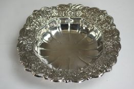 A white metal (tests as silver) repousse floral and foliate design plate with linear indentations to