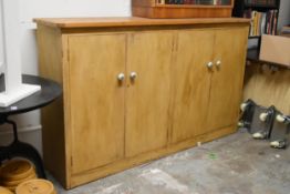 A vintage distressed painted pine housekeepers cabinet with panel doors enclosing shelves on a