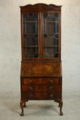 An early 20th century figured walnut bureau bookcase, with two glazed doors enclosing shelves over a
