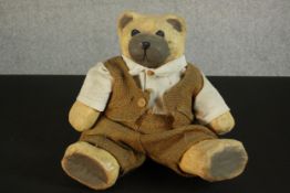 A painted papier mache teddy bear in a hessian suit. H.37 W.28 D.12cm.