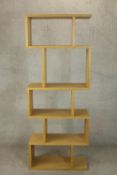 A contemporary light oak room divider, with an arrangement of open shelves. H.180 W.70 D.30cm.