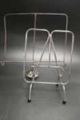 A silver plated modernist magazine rack raised on pad feet together with a chrome plated magazine