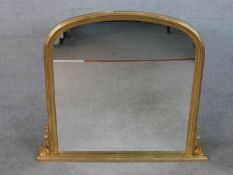 A contemporary Victorian style gilt framed overmantel mirror with a rounded top, flanked by carved