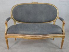 A French Louis XVI style carved giltwood canape, upholstered in grey fabric to the oval back, the