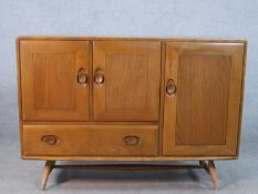 A mid 20th century Ercol beech and elm sideboard, with two cupboard doors above single drawer and