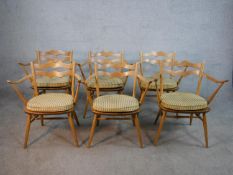 A set of six mid 20th century Ercol blonde elm and beech open arm and splat back dining chairs model