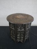 A carved Indian hardwood folding occasional table, the circular top densely carved with fruiting