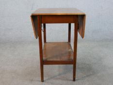 A mid 20th century mahogany drop leaf table with shelf undertier raised on square tapering
