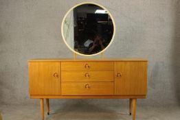 A circa 1960s Schreiber teak dressing table, with a circular mirror over three central short