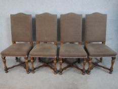 A set of four hump back dining chairs, upholstered in brown fabric to the back and seat, raised on