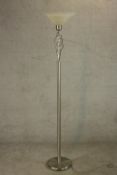 A contemporary polished and brushed steel floor standing uplighter lamp, with a glass shade over
