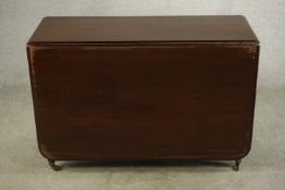A George III mahogany drop leaf gateleg dining table raised on turned supports terminating in