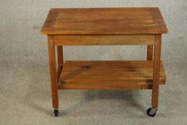 A mid 20th century slatted teak two tier trolley, raised on castors. H.62 W.76 D.50cm.