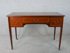 An Edwardian inlaid mahogany three drawer dressing table raised on tapering supports terminating