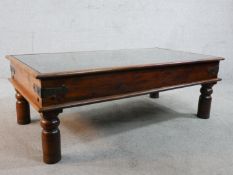 A 20th century carved hardwood, possibly African, 'shield' inset rectangular glass topped coffee