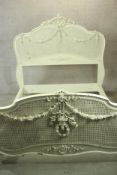 A 20th century painted hardwood and bergère single bed frame, with applied wreath and swag