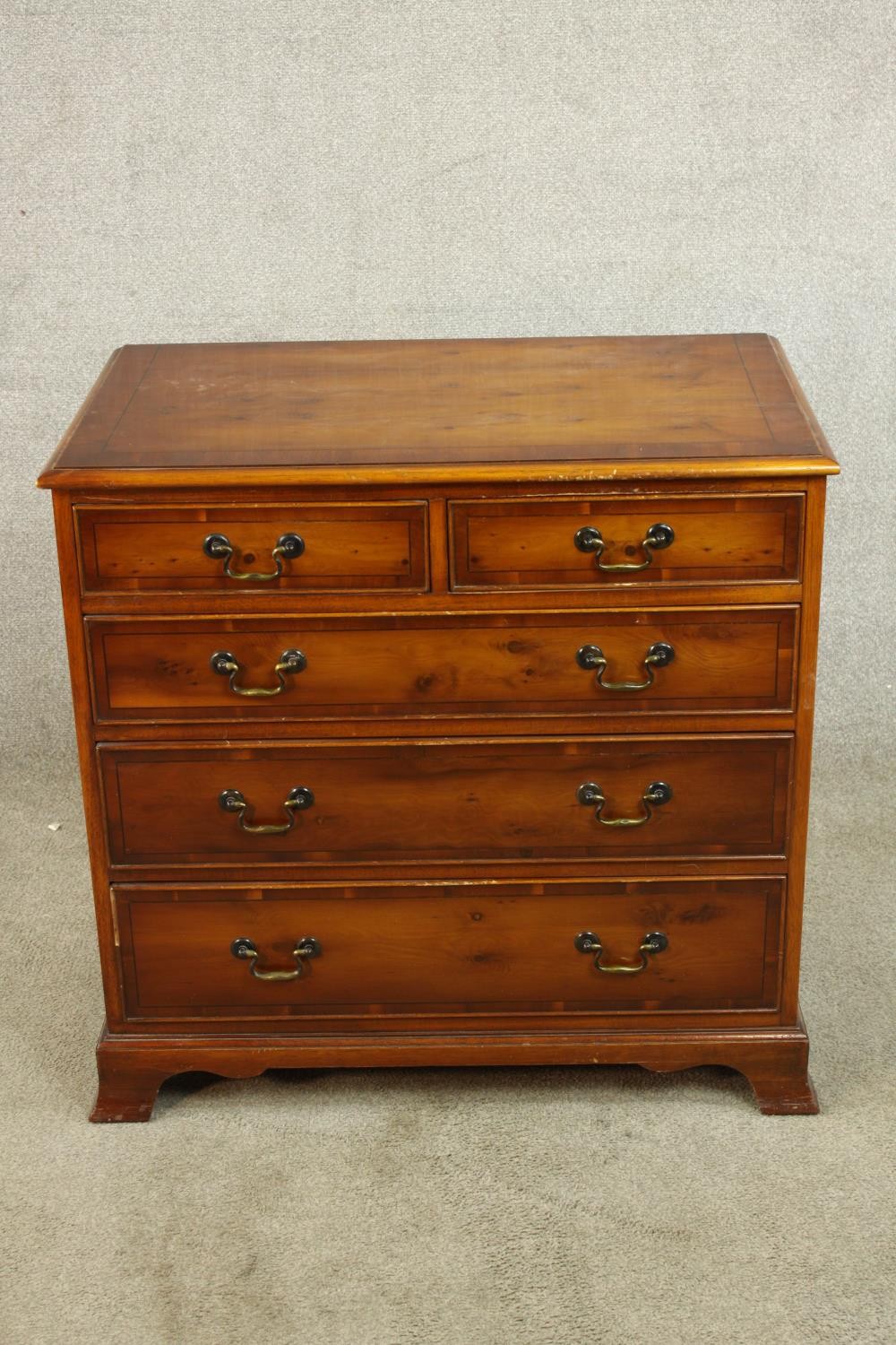 A contemporary chest of two short over three long graduating drawers with brass swing handles raised