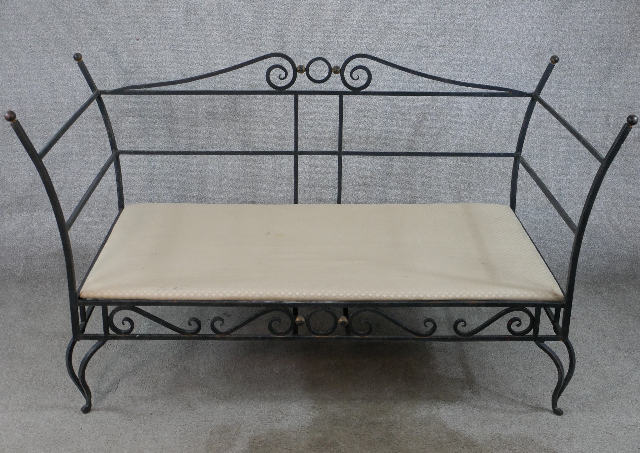 A contemporary painted iron garden two seater settee raised on pierced scrollwork style cabriole