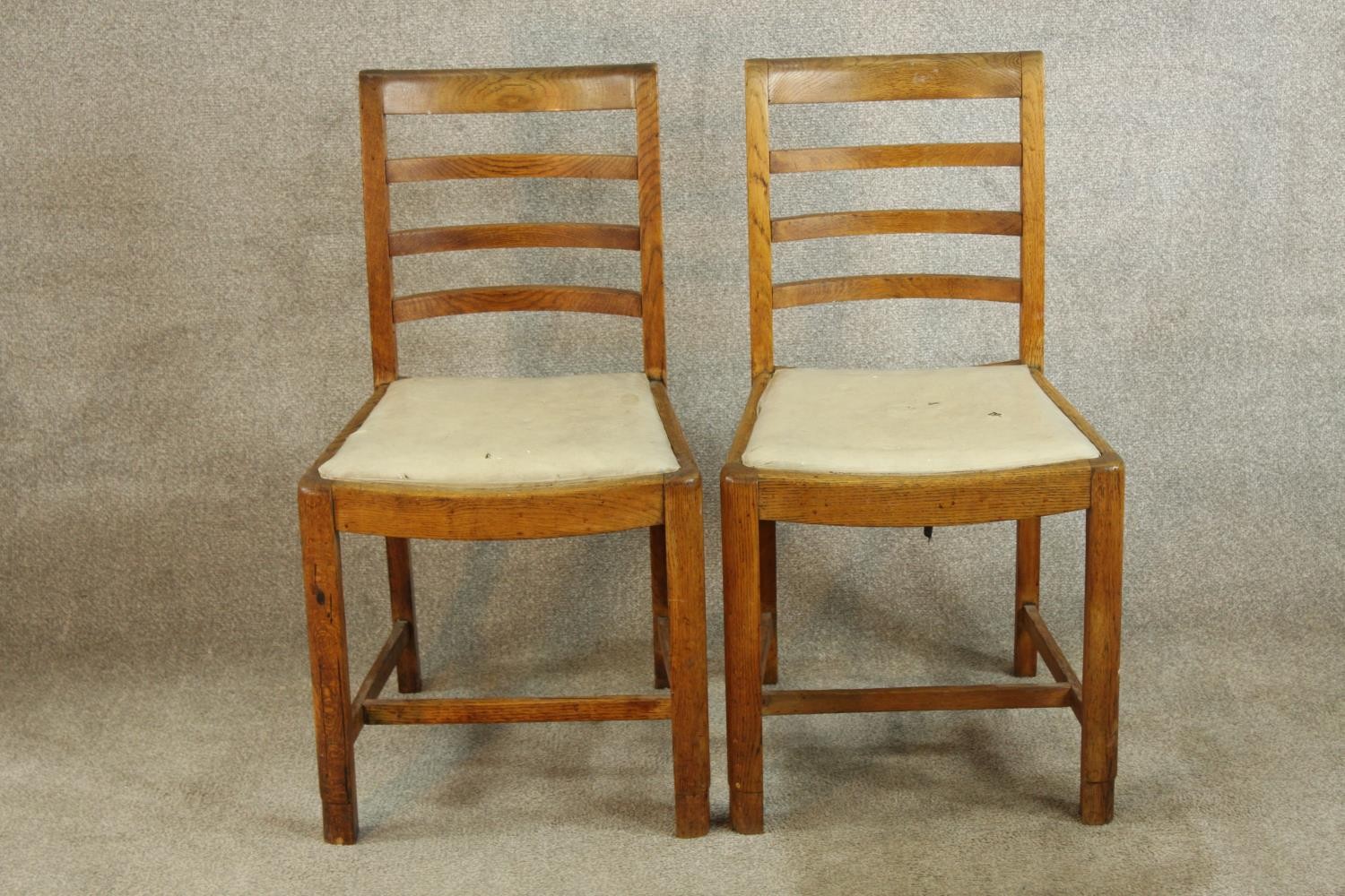 A pair of early 20th century oak framed ladder back chairs, raised on carved supports with drop in