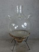 A contemporary clear glass terrarium housed in a wicker base raised on metal base with outswept