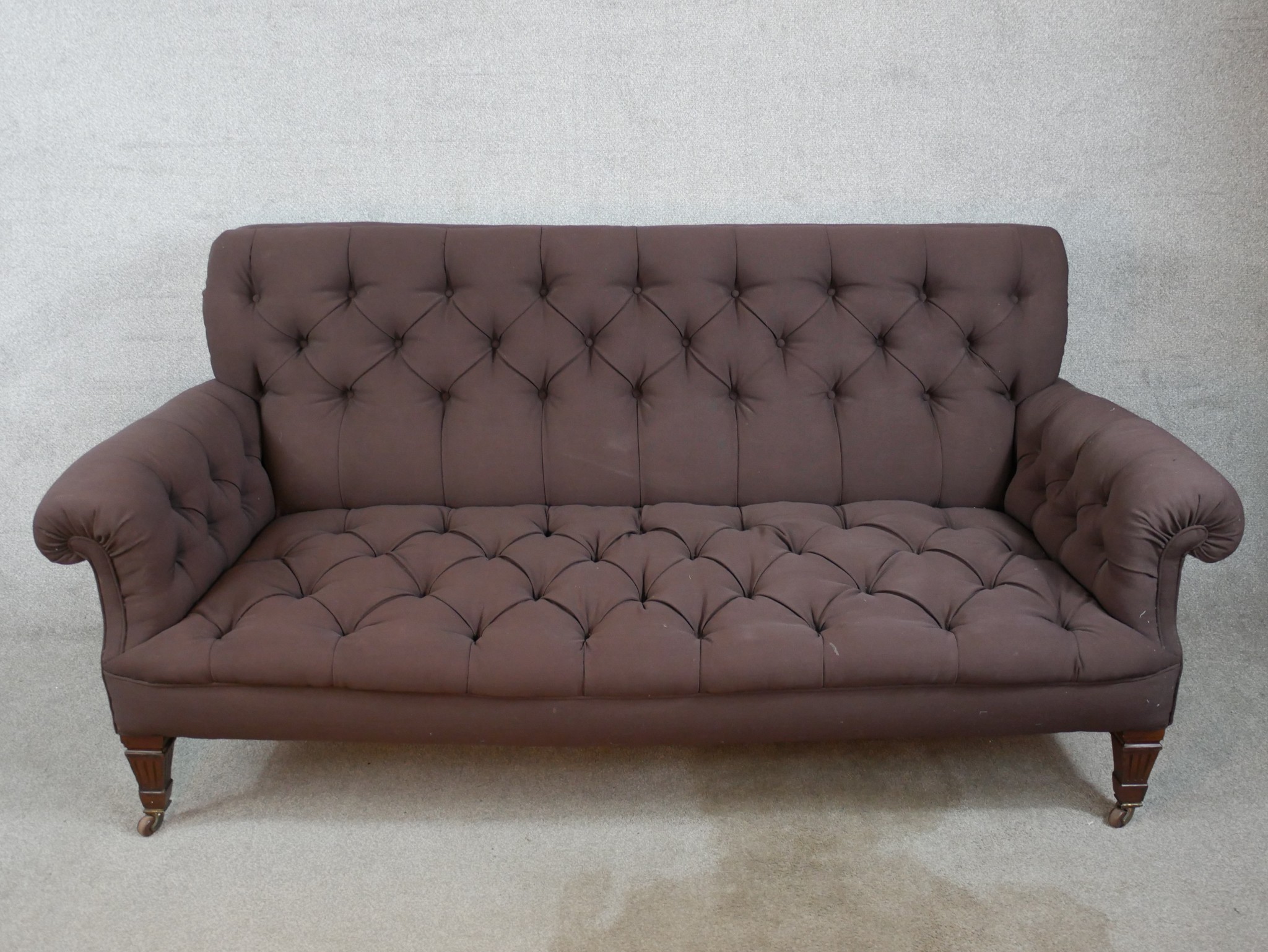 A late 19th century mahogany framed button upholstered scroll arm settee, raised on square