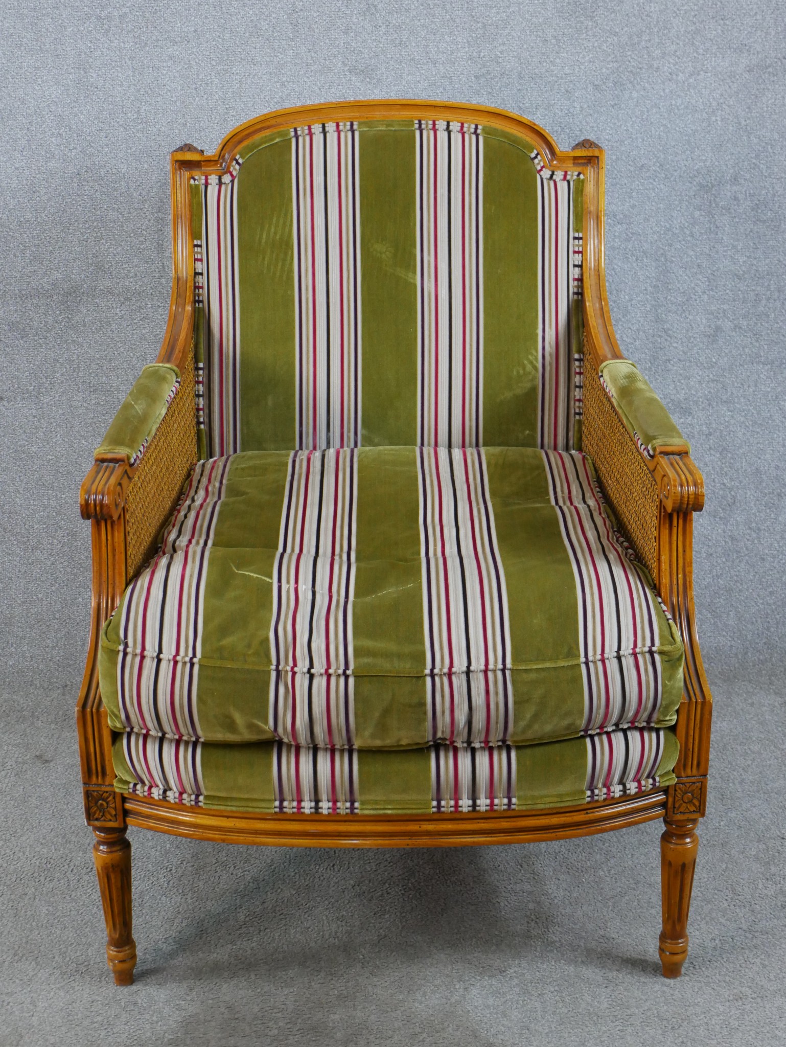 A late 19th/early 20th century walnut and bergère framed French style armchair raised on fluted
