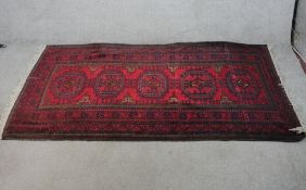 A 20th century red ground Persian woollen rug with four central lozenges within geometric border.